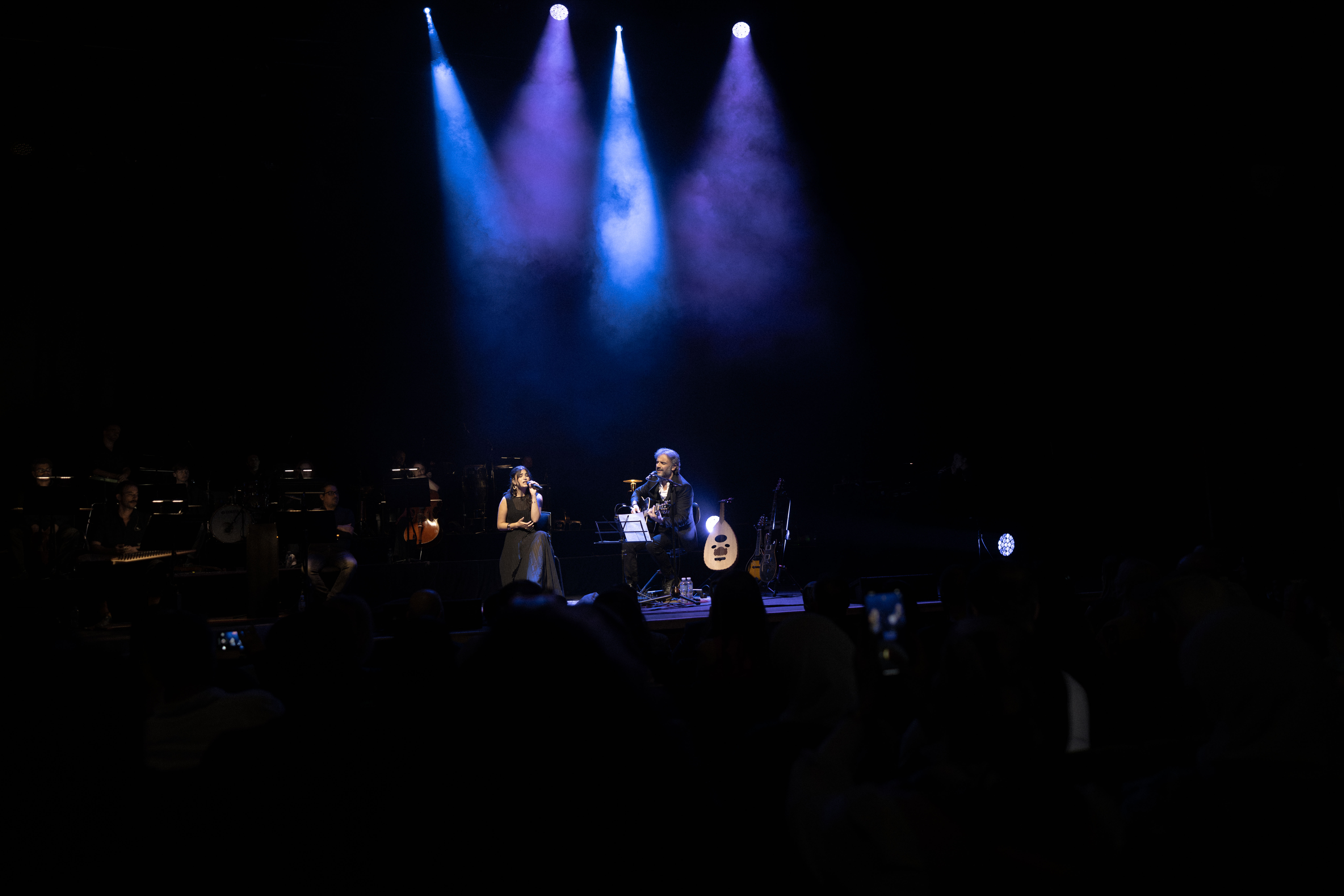 Lana Oudeh performing on a dark stage with blue lights